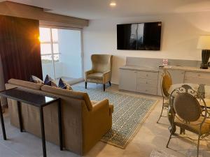 a living room with a couch and a table and chairs at Hotel HBlue Malecón in La Paz