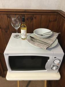 een witte magnetron met een fles wijn en een glas bij West Royd in Robin Hood's Bay