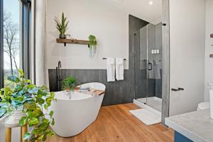 a bathroom with a white tub and a shower at Alpine Abode - Hot Tub, Nature in Brookville