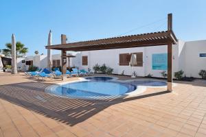 - une piscine dans un patio avec des chaises et une pergola dans l'établissement Playa Flamingo 34, à Playa Blanca