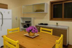 a kitchen with a wooden table with purple flowers on it at LSViver Hospedagem in Caxias do Sul +15 photos