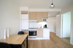 een keuken met witte apparatuur en een houten tafel bij Convenient Apartment for 2 in Kouvola