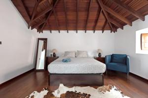 Un dormitorio con una cama y una silla azul. en Casa Gauguin, en Puntillo del Sol