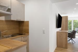 eine Küche mit weißen Schränken und einem TV an der Wand in der Unterkunft Ferienwohnung 1 Coburg-Creidlitz in Coburg