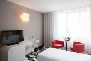 Habitación de hotel con cama, escritorio y TV. en Hotel Tristar en La Louvière