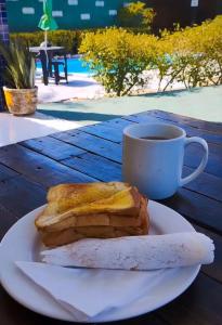 a sandwich on a plate next to a cup of coffee at Pousada e Hostel F C in Natal