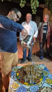 Oulad AkkouDartagounite的一个男人手里拿着一个锅，桌子前放着几杯玻璃杯。