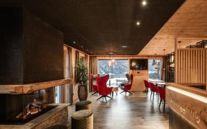 a living room with a fireplace and red chairs at Bruneggerhof Weissenbach in Rio Bianco
