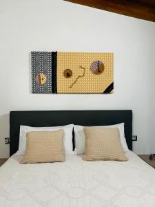 a bed with two pillows and a painting above it at Casa Ipogeo in SantʼAntìoco
