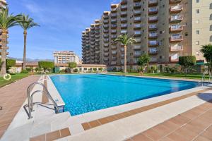 une piscine devant un immeuble avec des palmiers dans l'établissement Apartamento Son De Mar Gondolas, à Almuñécar