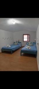 two blue beds in a room with a window at Lucky House Muravera in Muravera