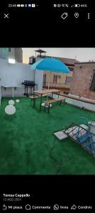 a patio with benches and a blue umbrella at Lucky House Muravera in Muravera