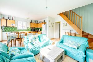 a living room with blue couches and a kitchen at Maison 12 personnes in La Bernerie-en-Retz