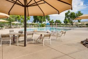 GermannにあるPool Access! Suburban Home 11 Mi to Dtwn Gilbertのプールの前にテーブルと椅子(パラソル付)