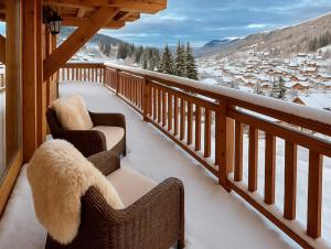 a balcony with two chairs and a view of a town at Chalet Luxury 5-Les Gets-Luxe-confort-jacuzzi-à 400 m des pistes et vue montagne Mont Chéry in Les Gets