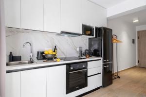 una cucina con mobili bianchi e un frigorifero nero di Mella Roa - Emer a Nikiana