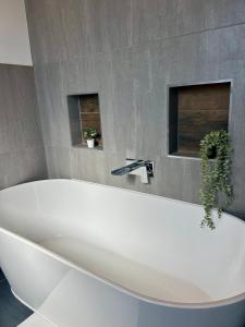 a white bath tub in a bathroom with two windows at The Crescent Villa Lancing in Lancing +17 photos