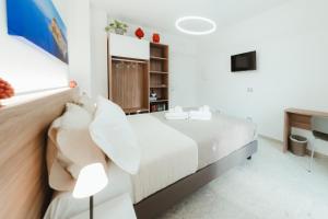 a white bedroom with a bed and a television at Verga 16 Deluxe Cefalù Apartments in Cefalù