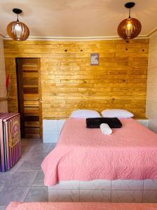 a bedroom with a pink bed with wooden walls at Pousada Maria Bonita Abreu e Lima in Maricota