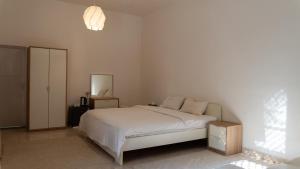 a white bedroom with a bed and a mirror at بيت الشّاب Al Shab House in Ţīwī +82 photos