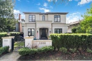 a large white house with a gate and bushes at Family guest suite in Marpole in Vancouver
