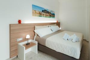 a bedroom with a large bed with a wooden headboard at Verga 16 Deluxe Cefalù Apartments in Cefalù