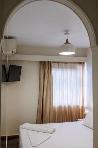 a bedroom with a white bed and a window at Ruby Rooms Kifisia in Athens