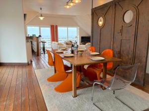 ein Esszimmer mit einem Holztisch und orangefarbenen Stühlen in der Unterkunft Villa Armoréa in Sibiril