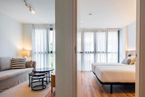 a bedroom with a bed and a couch and a table at Brabo Apartments in Hospitalet de Llobregat