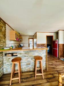 una cocina con 2 taburetes de madera y una barra en Casa, en Punta Arenas