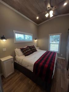 a bedroom with a bed with a striped blanket and two windows at Carolina Camp Cedar in Pickens