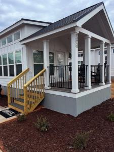 a small white house with a porch and stairs at Carolina Camp Cedar in Pickens