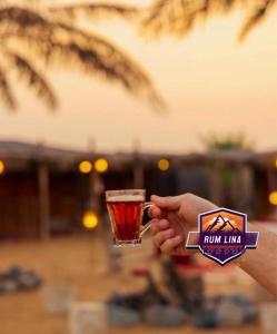 una persona sosteniendo una bebida en un vaso en RUM LINA lUXURY CAMP, en Wadi Rum