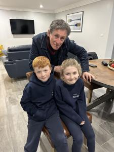 a man sitting next to two children sitting on a chair at BayView Lodge 4-Bedroom Penthouse Apartment in Downings