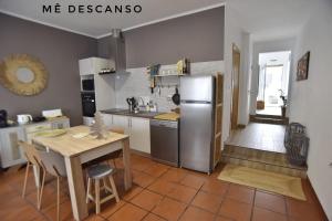 a kitchen with a table and a stainless steel refrigerator at O mê descanso in Vimieiro
