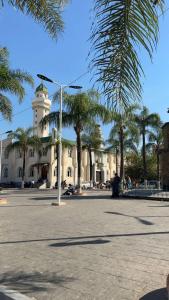 a building with a clock tower and palm trees at Bayt Nour - Alger Riyadh City Oued El Moussa in Ouled Moussa +40 photos