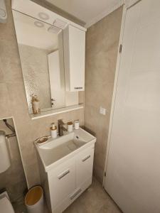 un bagno con un lavandino bianco e uno specchio di Apartman Mona a Sarajevo Altre 7 foto