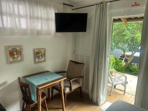 een eetkamer met een tafel, stoelen en een televisie bij Aruã Suítes & Café in Penha