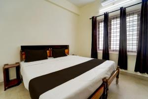 a bedroom with a black and white bed with windows at Collection O Govt Engineering College Formerly Anby Plaza in Trivandrum
