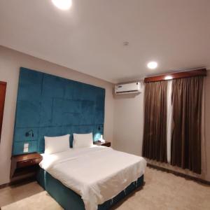 ein Schlafzimmer mit einem großen Bett mit blauem Kopfteil in der Unterkunft شقق ترف الليل للشقق المخدومة in Ash Shuqayq