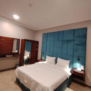 ein Schlafzimmer mit einem großen Bett mit blauem Kopfteil in der Unterkunft شقق ترف الليل للشقق المخدومة in Ash Shuqayq