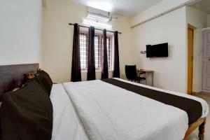 a bedroom with a white bed and a television at Collection O Govt Engineering College Formerly Anby Plaza in Trivandrum