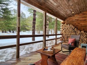 Stylish Forest Lodge with Large Hot Tub, Firepit and Fireplace minutes to Gore Mountain في North Creek: شرفة كابينة مع طاولة وكرسي
