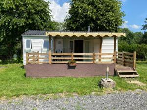 een tiny house met een veranda en een terras bij CAMPING de la BUGE in Rochefort-Montagne