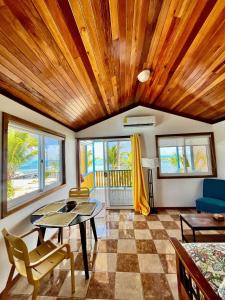 un soggiorno con soffitto in legno, tavolo e sedie. di Colinda Cabanas a Caye Caulker