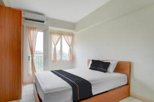 een slaapkamer met een bed en een raam bij OYO 94837 Apartment Ekki Tower in Tjikuda Dua