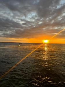 un barco en el océano con la puesta de sol en el fondo en Tanjungmansuarhomestay, en Poelau Mansoear