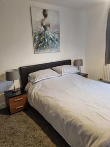 a bedroom with a bed with two lamps and a painting on the wall at Spacious 3BR Home with Large Garden - Ashford, Kent in Kennington