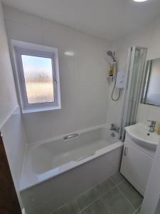 a white bathroom with a tub and a sink at Spacious 3BR Home with Large Garden - Ashford, Kent in Kennington