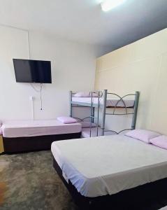 a room with two beds and a flat screen tv at Hospedagem Santa Gertrudes Comensoli in Cachoeira Paulista